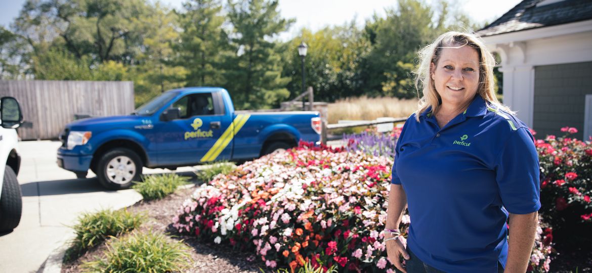 Lisa Fazio standing in front of flowerbed with a perficut truck in the background.