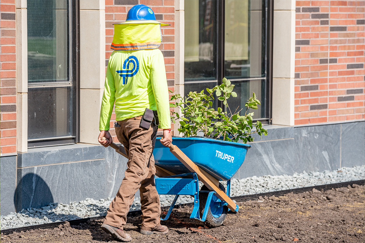 team member with wheel barrow wearing a hat and sun shade