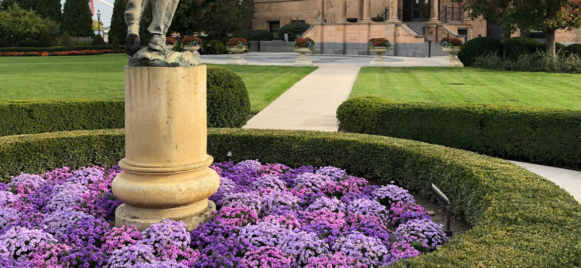 purple mums in a large outdoor planter around a statue at the world food prize in des moines, iowa