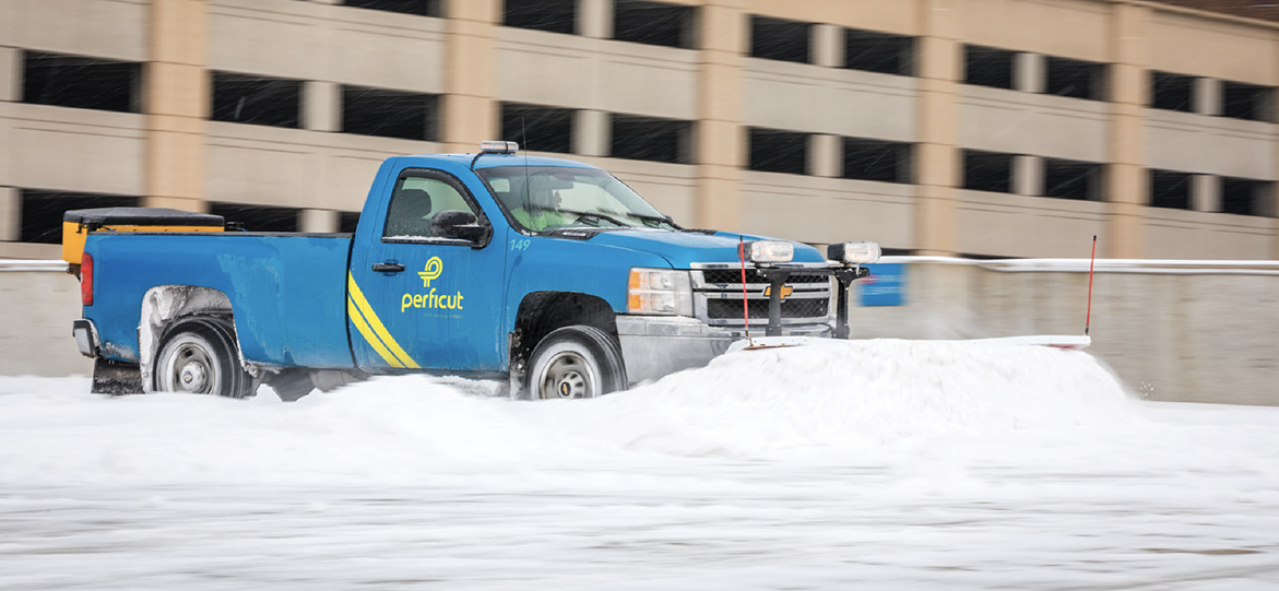 Team Perficut truck with a snow plow on top of parking garage