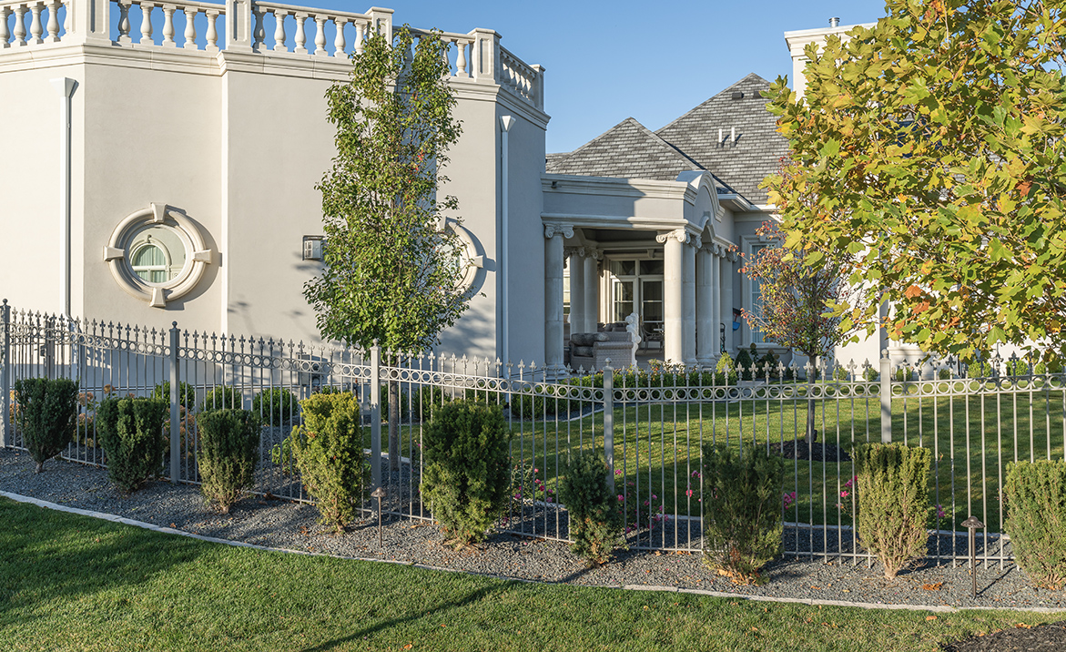 Residential landscaping with trees and hedges along fence