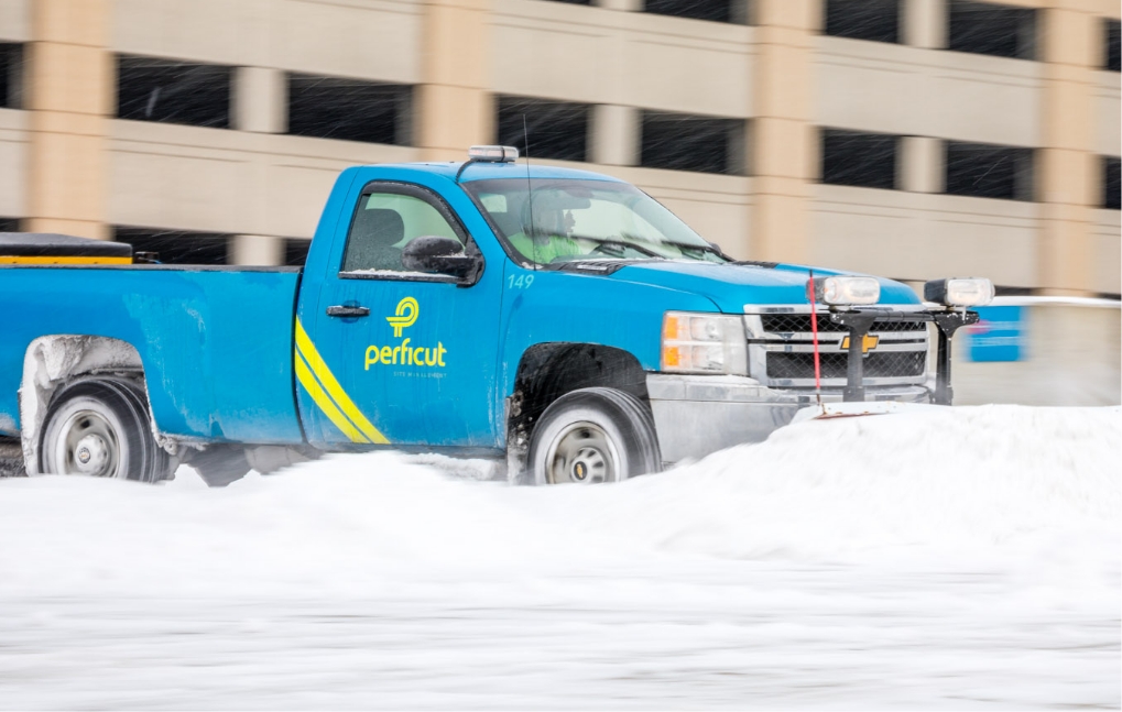 Commercial Snow and ice management blue Perficut truck pushing snow on parking deck